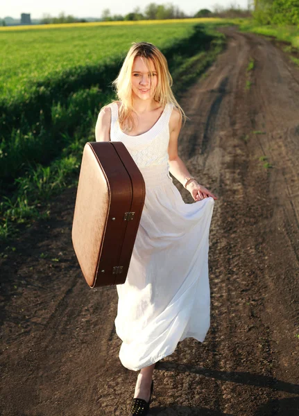Όμορφη ξανθιά κοπέλα σε μακρύ λευκό φόρεμα με βαλίτσα — Φωτογραφία Αρχείου