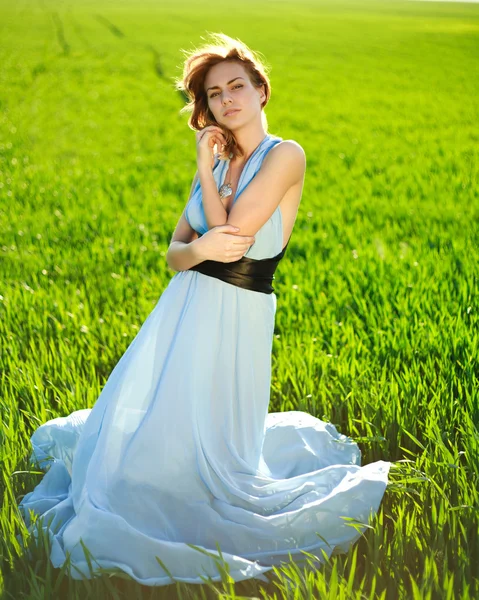 Mladá žena v dlouhé modrých šatech líbí slunečný den — Stock fotografie