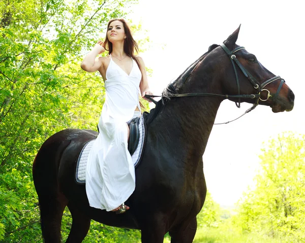 年轻漂亮的女孩骑着马在绿色森林 — 图库照片