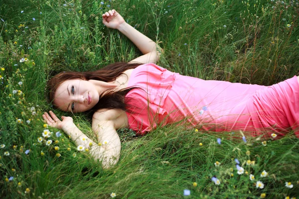 Bela menina sonhos, deitado no prado na primavera — Fotografia de Stock