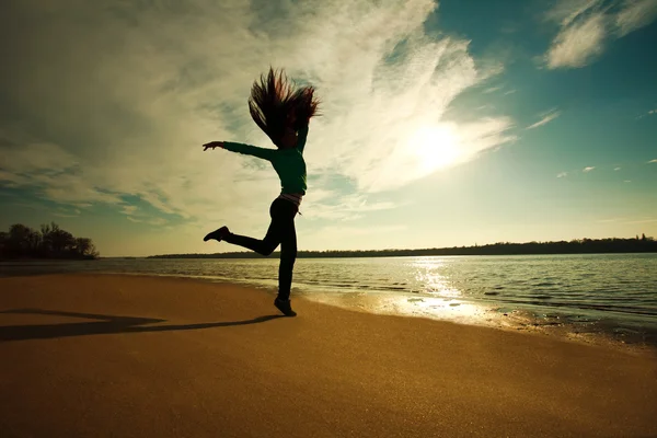 Mujer saltando en la playa en el fondo del cielo soleado — Foto de Stock