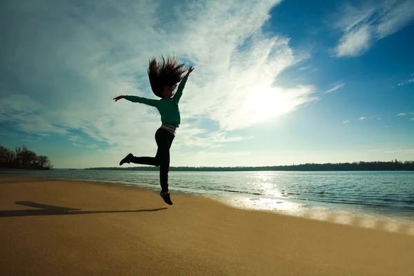 Donna che salta sulla spiaggia su sfondo cielo soleggiato — Foto Stock