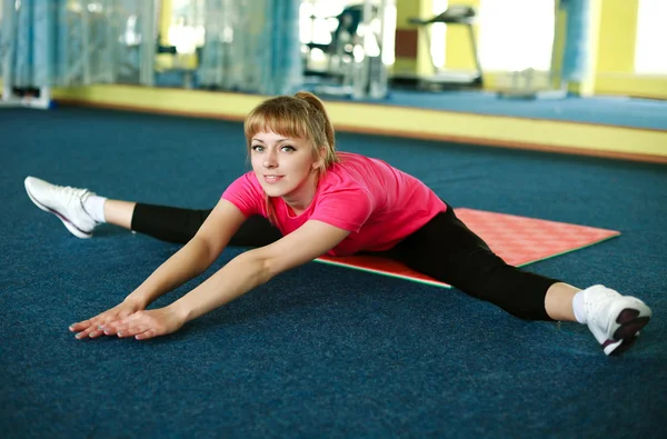 Mujer joven haciendo ejercicio de estiramiento en el gimnasio — Foto de Stock