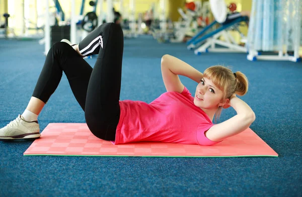 Молодая женщина делает упражнения на растяжку в спортзале — стоковое фото