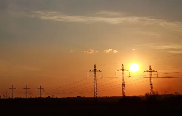 高电力送电线路铁塔在戏剧性的日落背景 — 图库照片