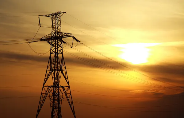 Alta potência torres de linha elétrica no dramático pôr do sol fundo — Fotografia de Stock