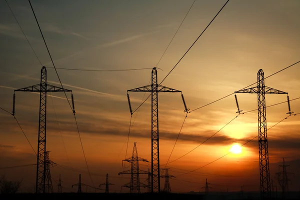 高功率电线路杆塔在戏剧性的日落背景 — 图库照片