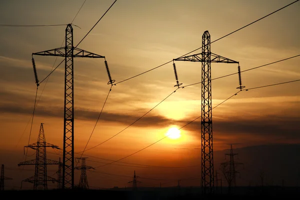 Wysoka moc elektryczna linia wieże na tle zachodu słońca — Zdjęcie stockowe