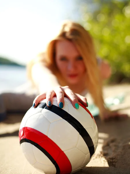 Flicka på stranden bakom fotbollen på nära håll — Stockfoto
