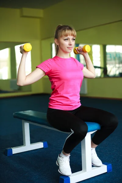 Спортивная девушка делает упражнения с гантелями в спортзале — стоковое фото