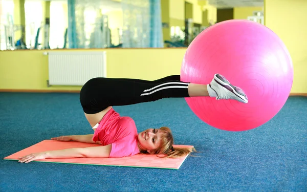 Νεαρή γυναίκα γυμνάζεται με μπάλα γυμναστικής στο γυμναστήριο — Φωτογραφία Αρχείου