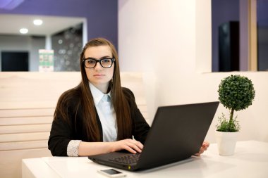 bir dizüstü bilgisayar ile ofiste çalışan genç iş kadını