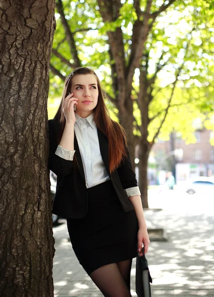 Ung affärskvinna prata i telefon utanför under ett träd — Stockfoto