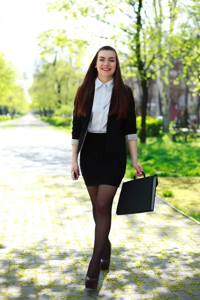 Jovem mulher de negócios feliz está andando dia de verão no parque da cidade — Fotografia de Stock