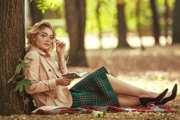 レトロなスタイルの若い女性 自然の中で公園の学生は眼鏡をかけてメモ帳を手に — ストック写真