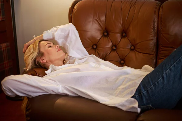 Happy Dreamy Woman Lies Leather Brown Sofa Home Room — Stock Photo, Image