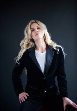 Lovely business lady in black suit, portrait of woman with long blond curly hair