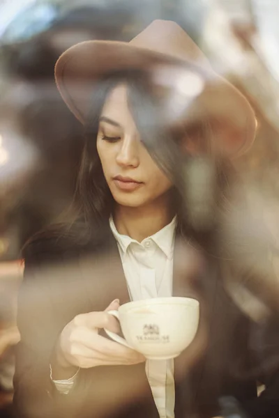 穿着经典商务风格的年轻亚洲女人 坐着沉思地凝视着窗外街道的反光和一杯咖啡的灯光 — 图库照片