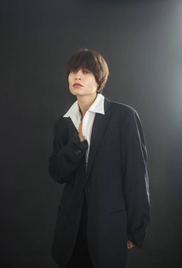Portrait of a sad and sorrow young woman on a black background in a business suit of an office worker, manager