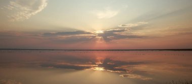 Rüya gibi ve dramatik gün batımı gökyüzü su yüzeyinin yansımalarında bulut var.