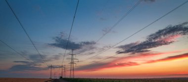 Yol üzerindeki elektrik direkleri ve kablolar dramatik günbatımı arkaplanında