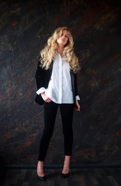 Gorgeous business lady in a black suit and white shirt on a black background, portrait of a beautiful woman