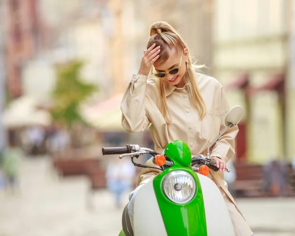 在欧洲一个古老城市的大街上 穿着外套 戴着黑色眼镜 骑着复古摩托的时髦女孩 — 图库照片