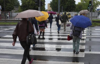 İnsanlar yağmurda yürür, yaya geçidinde ... 