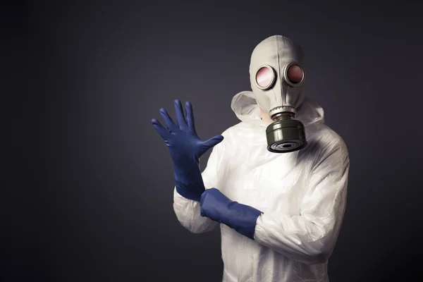 Homem com uma máscara de gás colocando em suas luvas — Fotografia de Stock