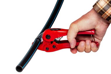 Tesisat araçları izole edildi. Bir adam, kırmızı bir pvc boru kesicisiyle bir parça PE basınç borusunu ya da su borusunu kesin olarak keser. Kesme yolu. İçme ve hizmet su sistemleri.