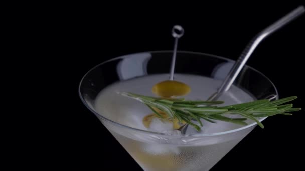Droge martini met rozemarijn en groene olijven op een zwarte achtergrond. — Stockvideo
