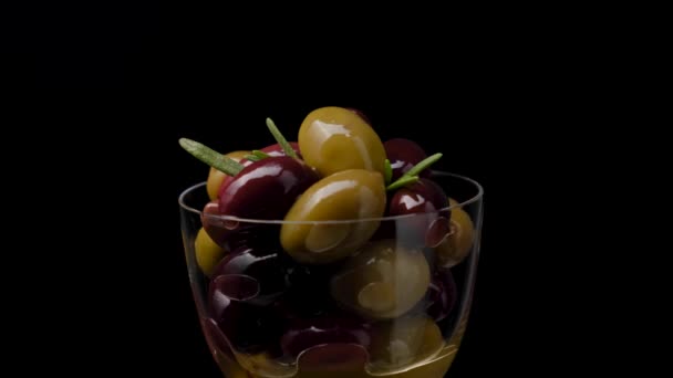 Gemarineerde Gemengde olijven met stenen in een glazen schaal. Zwarte achtergrond. — Stockvideo