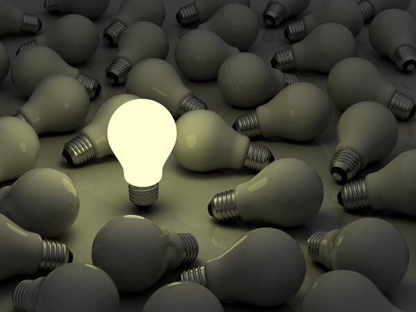 One glowing light bulb standing out from the unlit incandescent bulbs