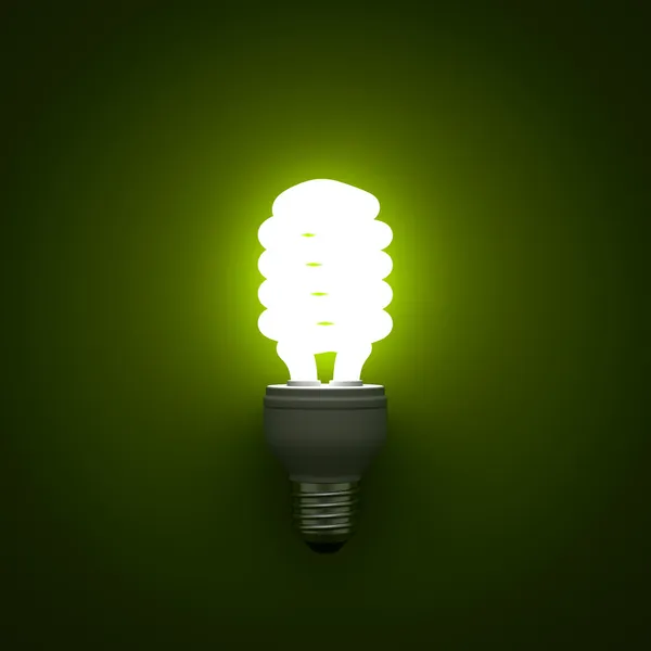 Energy saving compact fluorescent light bulb glowing over green background — Stock Photo, Image