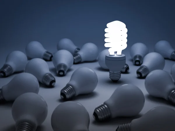 One glowing compact fluorescent light bulb standing out from the unlit incandescent light bulbs — Stock Photo, Image