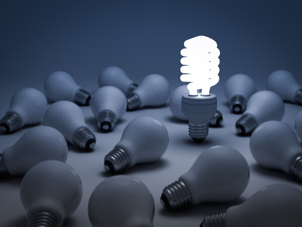 Одна светящаяся компактная люминесцентная лампочка, выделяющаяся из неосвещенных лампочек накаливания
