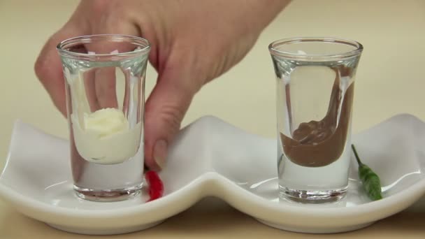 Att sätta färska chilifrukter i smält choklad i en rad med snapsglas. — Stockvideo