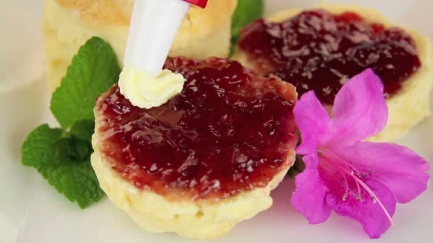 Leidingen zoete slagroom op een scone jam. — Stockvideo