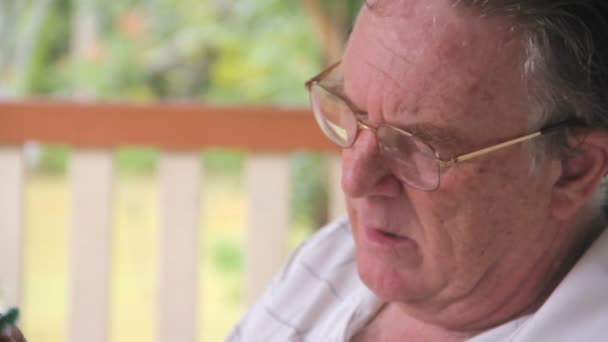 Reifer Mann sitzt auf seiner Veranda und spielt Sudoku. — Stockvideo