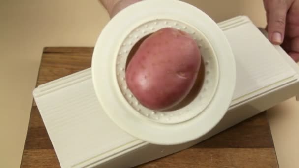 Slicing a fresh potato with a mandoline which is a slicer with a blade. — Stock Video