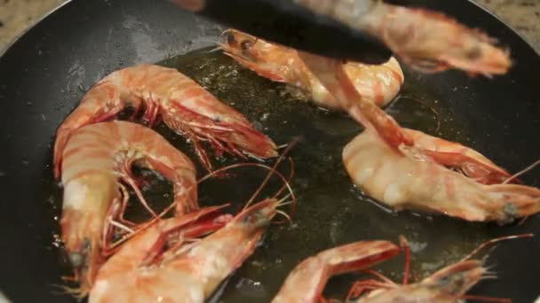 Camarones enteros se fríen en una sartén con aceite que se da vuelta con pinzas . — Vídeos de Stock