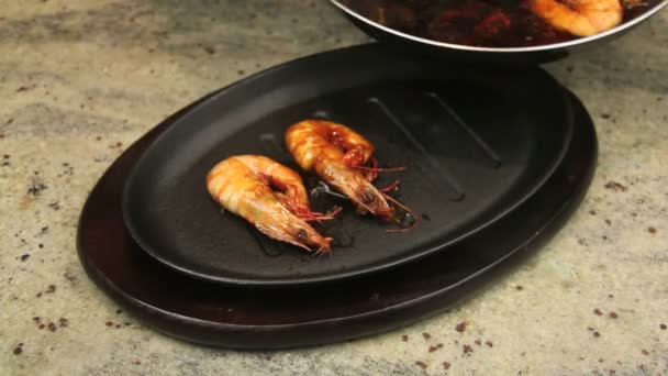 Fried shrimps being put in a baked hot iron pan and sizzling with asian marinade being poured over them. — Stock Video