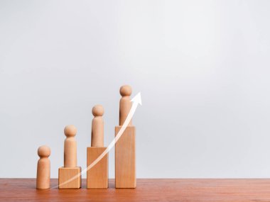 Nüfus artışı kavramı. Yükselen ok ve ahşap figürler, büyüyen bir grafik çizelgesinin üzerinde duruyor. Ahşap küpler, tahta masa ve beyaz arkaplan, fotokopi alanı ile düzenleniyor..