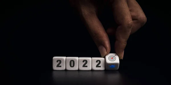 2021年改为2022年 目标是实现Covid 19局势概念 手动翻转白色骰子块 用于在黑暗背景下从病毒符号转换为目标图标 风格现代且简约 — 图库照片
