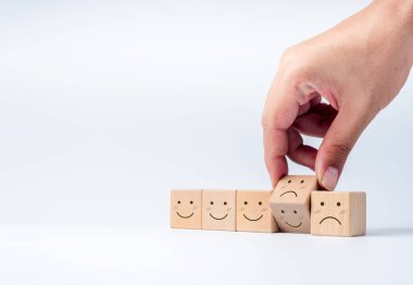 Beyaz arka planda gülen yüz yapmak için elleri ahşap küp bloklar çeviriyor. Müşteri değerlendirmesi ve değerlendirmesi. Müşteri seçimi. Müşteri hizmetleri değerlendirmesi ve tatmin araştırması kavramları.