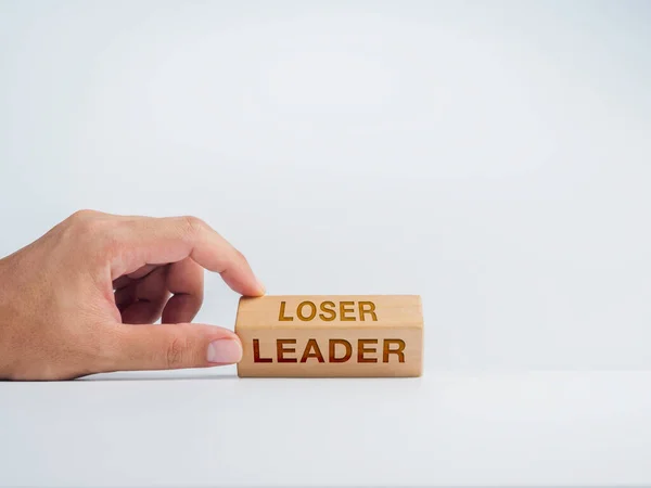 Changing to the Leader. Hand flip wooden cube blocks for changing words from loser to leader on white background, minimal style. Self-improvement, personal development, professional growth concept.