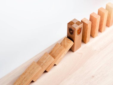 Kalkan güvenlik simgesi ayakta duran büyük tahta blok beyaza izole edilmiş domino taşlarını koruyor. Domino etkisini durduruyorum. İş veri yönetimi. Risk koruması.