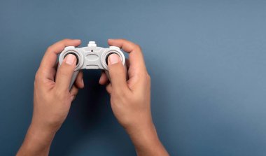 Mavi arka planda izole edilmiş, fotokopi alanı ve üst görünümü olan bir oyuncak için gümüş retro radyo uzaktan kumandası kullanılıyor. Oyun denetleyici joystick, düz konum, en düşük biçim.