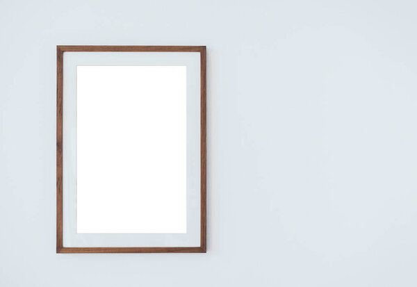 Mockup wooden square picture frame with mount, vertical style, isolated. Blank white on thin wood frame hanging on white wall background with copy space.