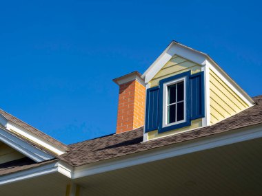 Sarı renkli pencereler, mavi gökyüzü arka planındaki büyük beyaz ahşap evin çatısındaki baca tuğlası dekorasyonuna yakın küçük oda, dış görünüşü fotokopi alanı olan..